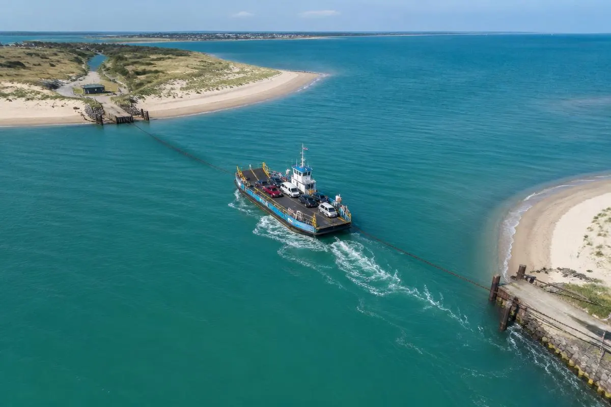 Aerial view of the Sandbanks chain ferry mid-crossing between two sandy shores at the mouth of Poole Harbour